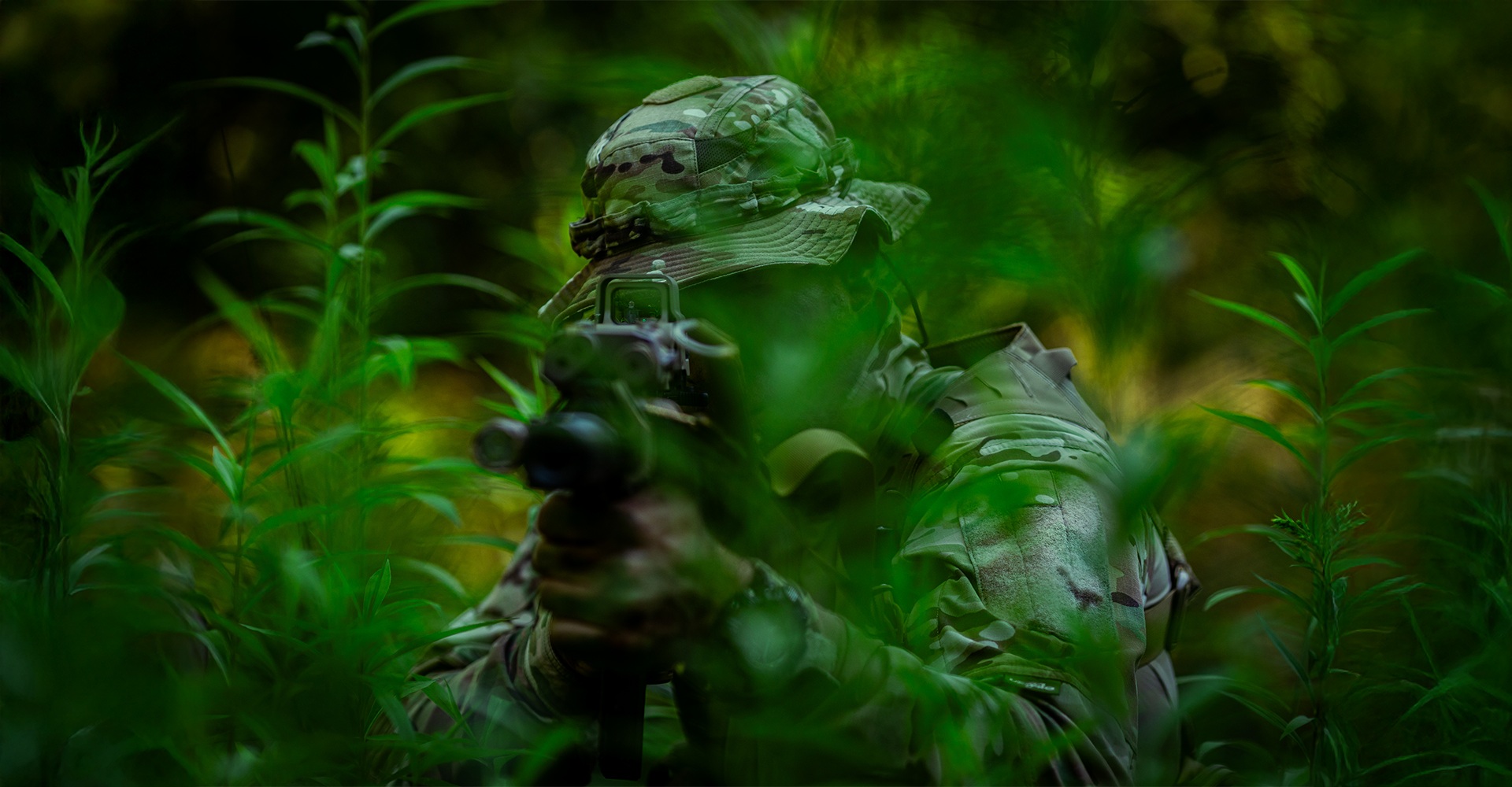 Operator in dense jungle foliage, aiming at a target with his firearm.